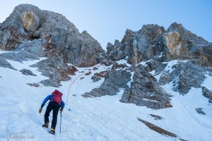 Sul canalone terroso e la traccia di salita alla forcella sulla cresta Ovest. Sulle rocce a destra del ripido canalino è evidente la grande "P" gialla descritta sulla guida del Berti.